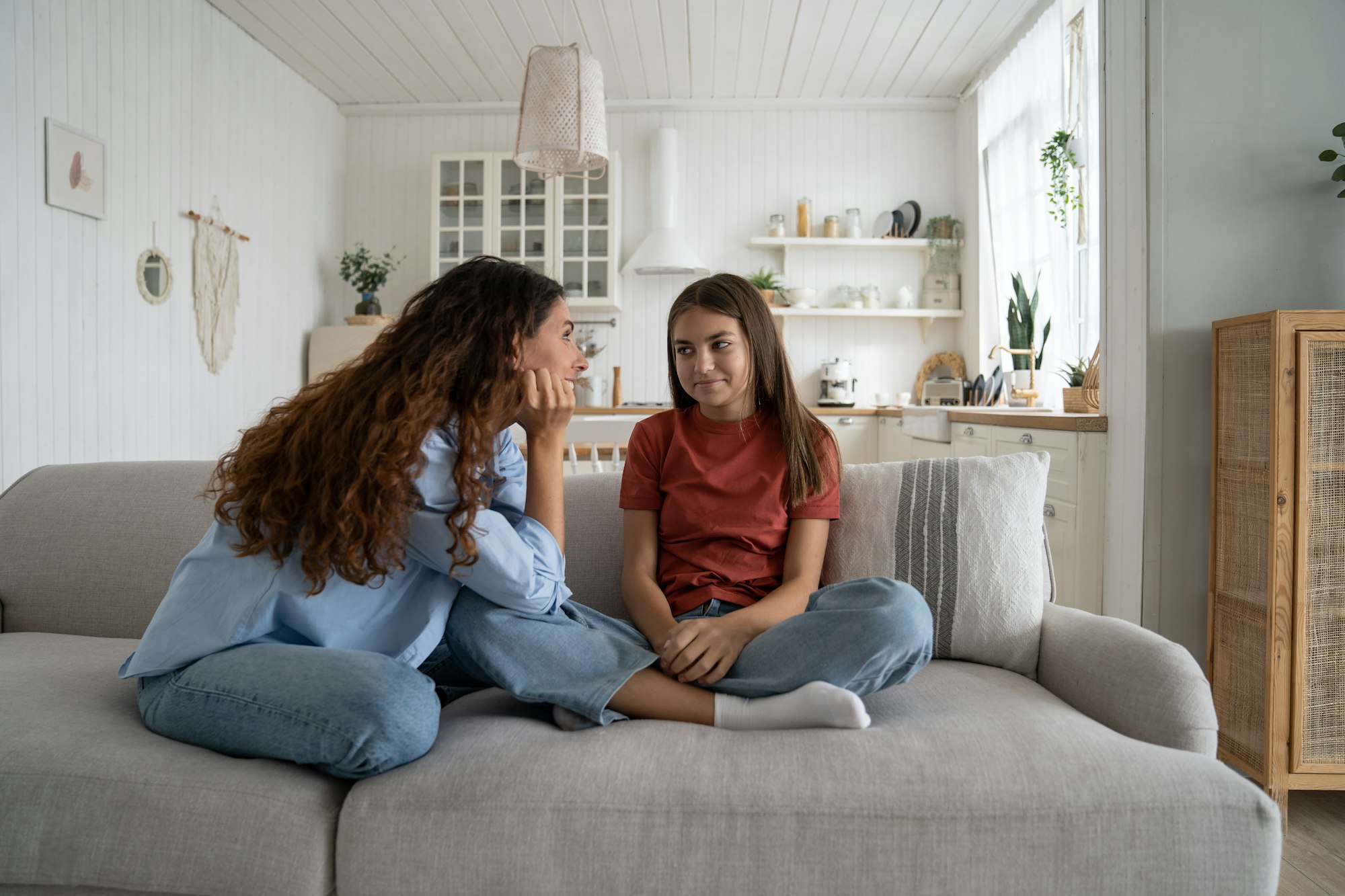 Teenage girl daughter talking with young loving supportive mother at home. Parent-teen relationships